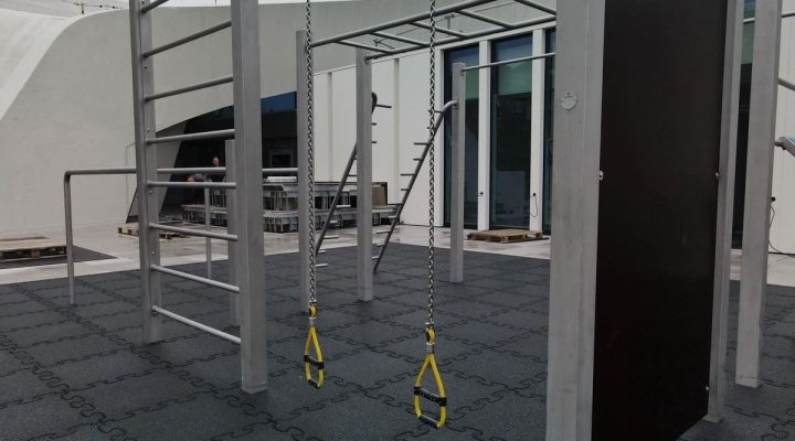 Calisthenics-Anlage mit grauem Fallschutz bei Sonnenschein