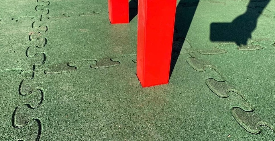 Grüne Fallschutzmatten um rote Pfosten schneiden