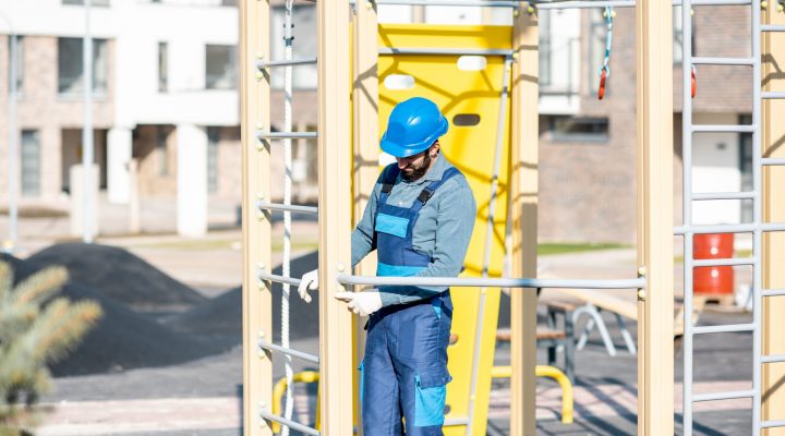 Ein Arbeiter prüft die Abstände eines Klettergerüstes auf dem Spielplatz