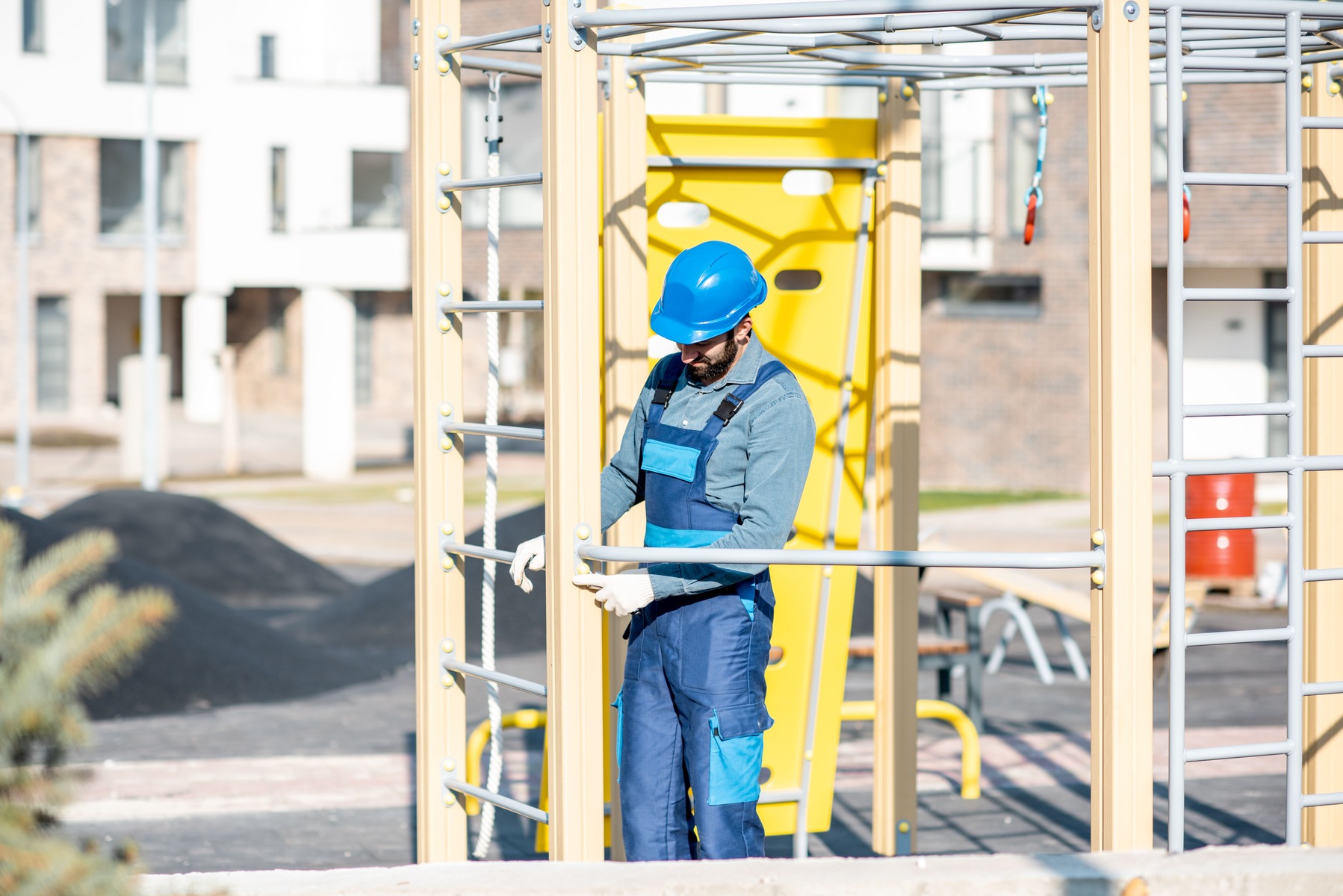 Ein Arbeiter prüft die Abstände eines Klettergerüstes auf dem Spielplatz